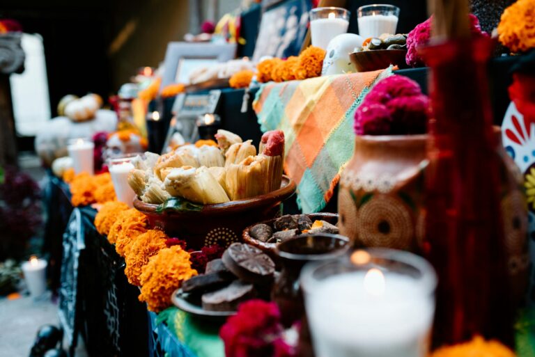 Colorful Day of the Dead altar with traditional offerings including tamales and candles in Guadalajara, Mexico.
